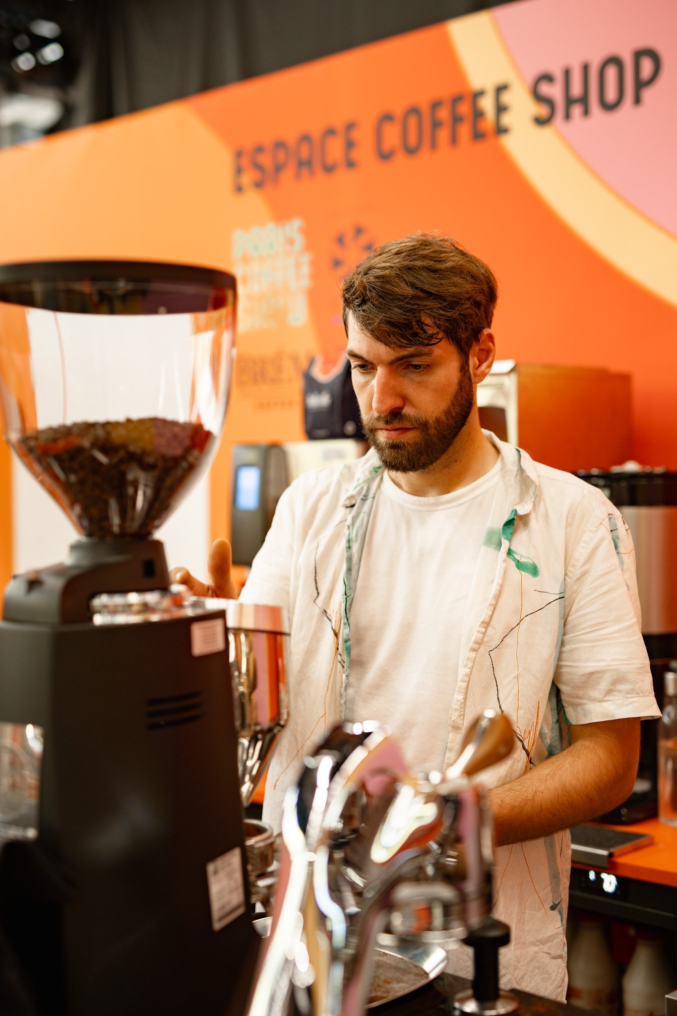 Christophe prépare un café, près d’un moulin et d’une machine à espresso.